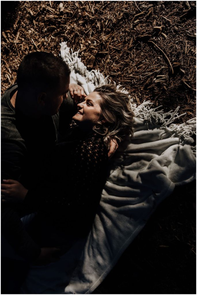 couple laying on blanket in forest