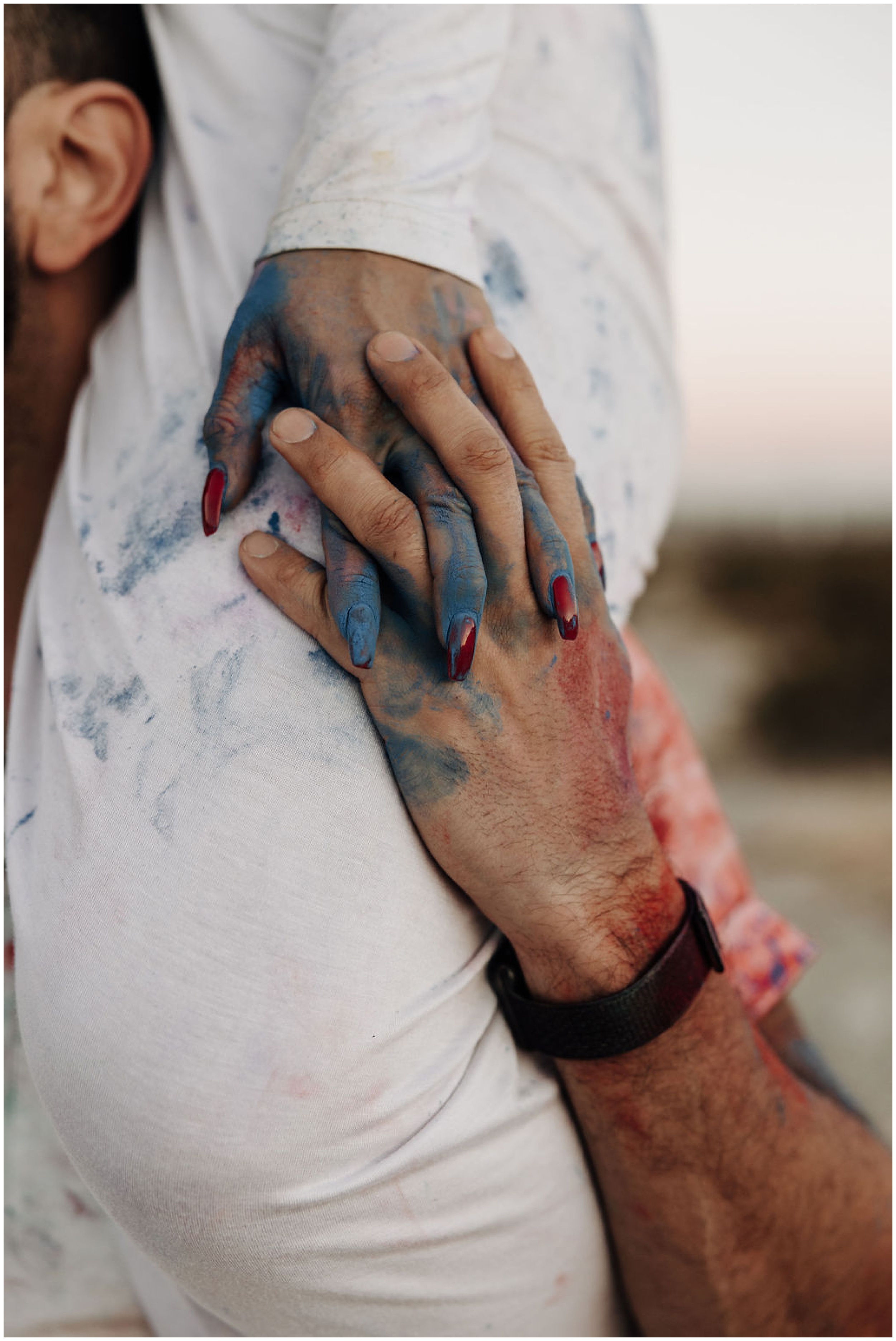 couple holding hands covered in colored powder